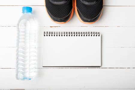 fitness equipment : running shoes,drinking water and notebook on white wood tableの写真素材