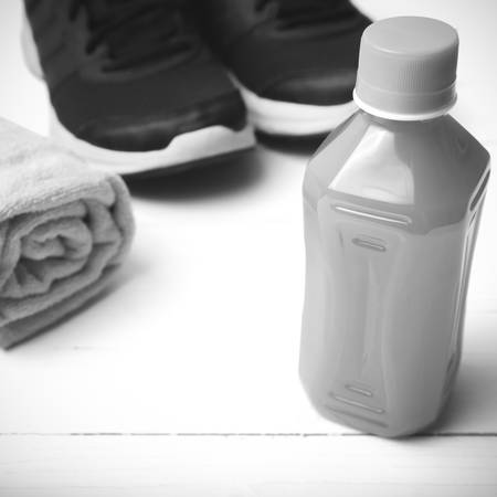 running shoes,towel and orange juice on white wood table black and white tone color styleの写真素材