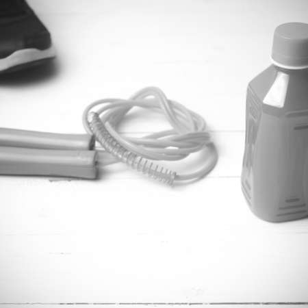 fitness equipment : running shoes,jumping rope and orange juice on white wood background black and white tone color styleの写真素材