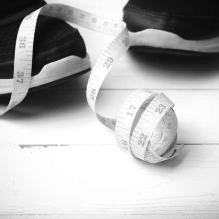 running shoes and measuring tape on white wood table black and white tone color styleの写真素材