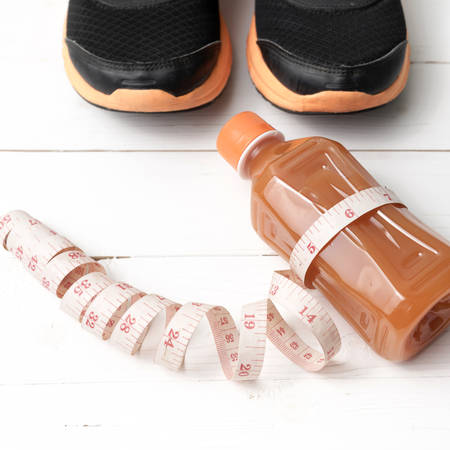 running shoes,orange juice and measuring tape on white wood backgroundの写真素材