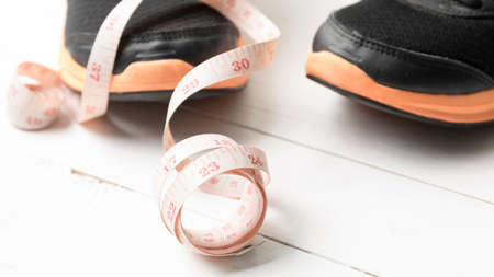 running shoes and measuring tape on white wood tableの写真素材