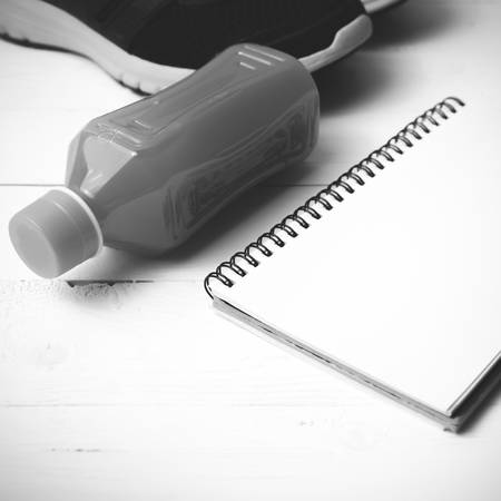 running shoes,orange juice and notepad on white wood background black and white tone color styleの写真素材