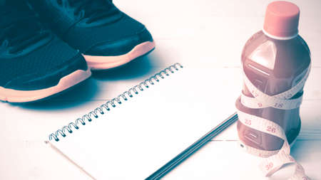running shoes,orange juice,measuring tape and notepad on white wood background vintage tone color styleの写真素材