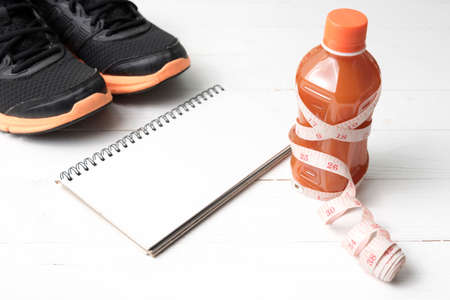 running shoes,orange juice,measuring tape and notepad on white wood backgroundの写真素材