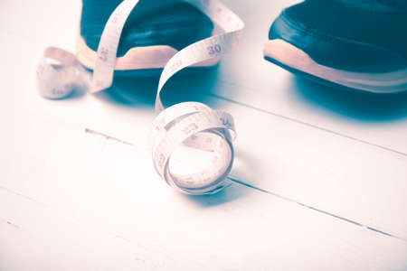 running shoes and measuring tape on white wood table vintage styleの写真素材