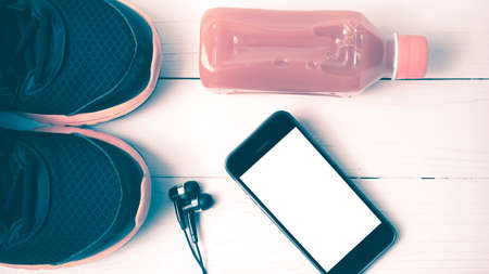 running shoes,orange juice and phone on white wood background vintage tone color styleの写真素材
