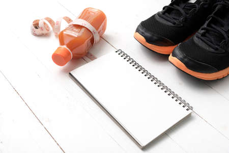 running shoes,orange juice,measuring tape and notepad on white wood backgroundの写真素材