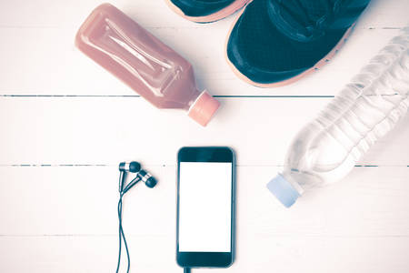 running shoes,orange juice,drinking water and phone on white wood background vintage tone color styleの写真素材