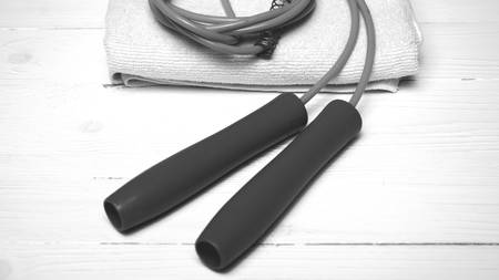 fitness equipment:white towel,jumping rope on white wood table black and white color styleの写真素材