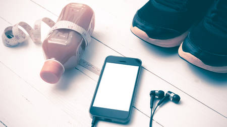 running shoes,orange juice,measuring tape and phone on white wood background vintage tone color styleの写真素材