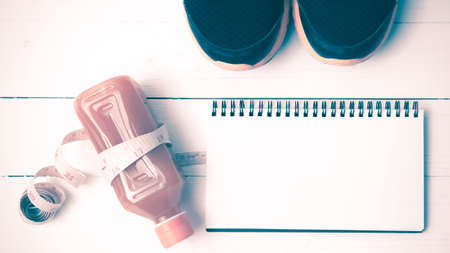 running shoes,orange juice,measuring tape and notepad on white wood background vintage tone color styleの写真素材