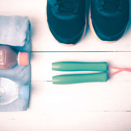 fitness equipment : running shoes,towel,jumping rope,drinking water and orange juice on white wood background vintage tone styleの写真素材