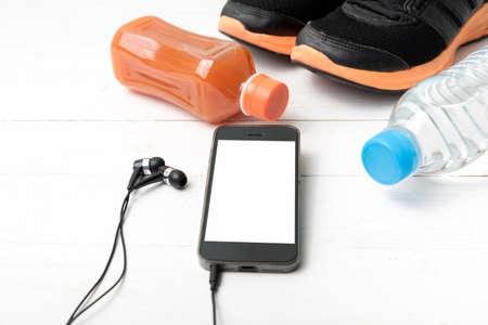 running shoes,orange juice,drinking water and phone on white wood backgroundの写真素材