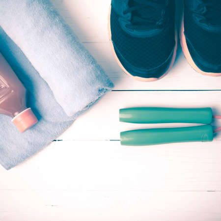 fitness equipment : running shoes,towel,jumping rope and orange juice on white wood background vintage tone styleの写真素材
