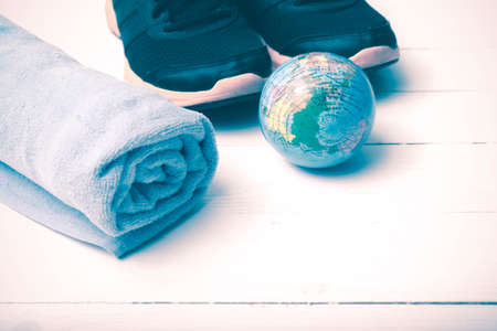running shoes,towel and earth ball on white wood table concept world healthy vintage styleの写真素材