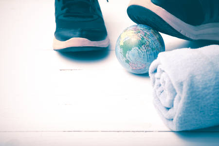 running shoes,towel and earth ball on white wood table concept world healthy vintage styleの写真素材