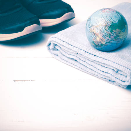 running shoes,towel and earth ball on white wood table concept world healthy vintage styleの写真素材
