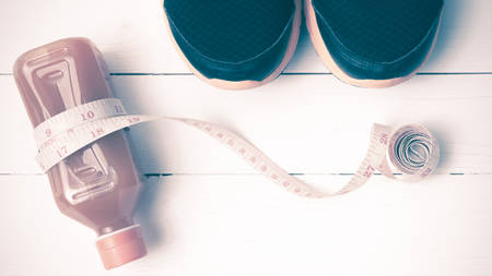 running shoes,orange juice and measuring tape on white wood background vintage tone color styleの写真素材