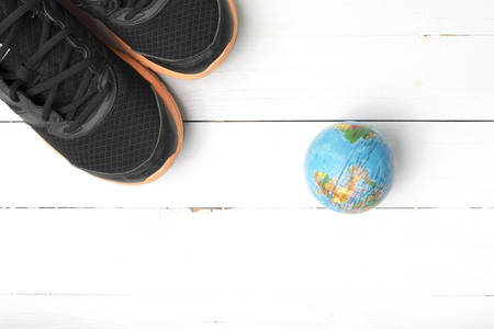 running shoes and earth ball on white wood table concept world healthy