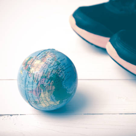 running shoes and earth ball on white wood table concept world healthy vintage style