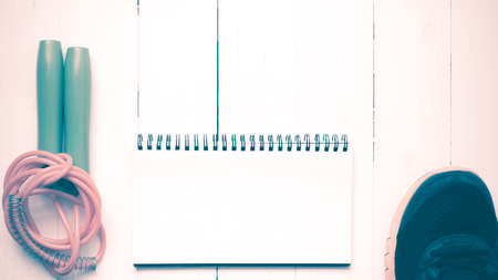 fitness equipment : running shoes,jumping rope and notepad on white wood table vintage styleの写真素材