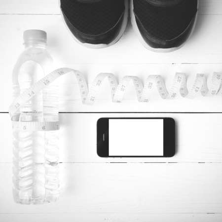fitness equipment : running shoes,drinking water,measuring tape and phone on white wood table black...