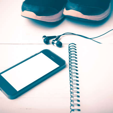 running shoes,notebook and phone on white wood table vintage styleの写真素材