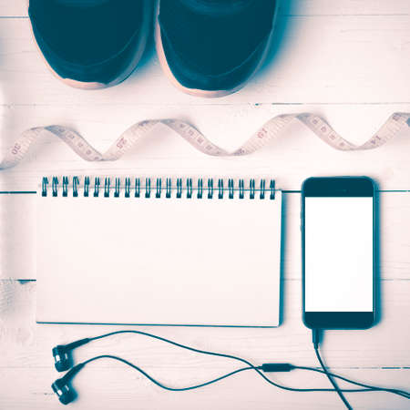 running shoes,measuring tape,notebook and phone on white wood table vintage styleの写真素材