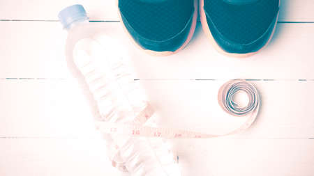 fitness equipment : running shoes,drinking water and measuring tape on white wood table vintage...