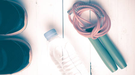 fitness equipment : running shoes,jumping rope and water bottle on white wood table vintage styleの写真素材