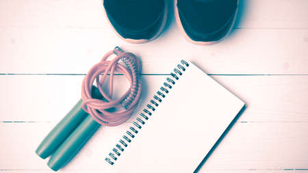 fitness equipment : running shoes,jumping rope and notepad on white wood table vintage style