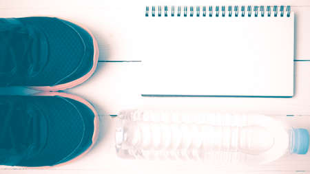 fitness equipment : running shoes,drinking water and notebook on white wood table vintage styleの写真素材