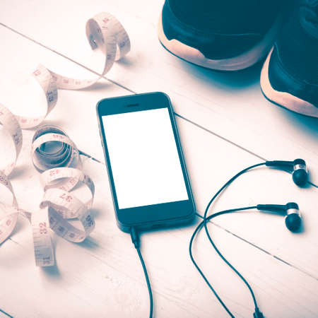 running shoes,measuring tape and phone on white wood table vintage styleの写真素材
