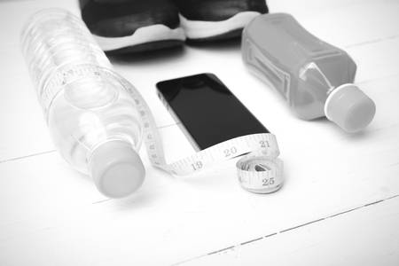 fitness equipment:running shoes,measuring tape,water,juice and phone on white wood background black...