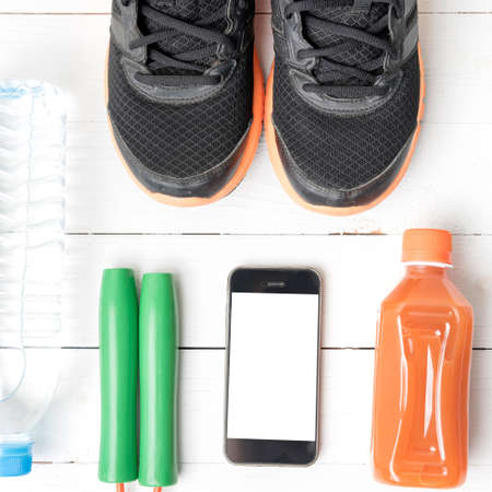 fitness equipment : running shoes,jumping rope,water,juice and phone on white wood backgroundの写真素材