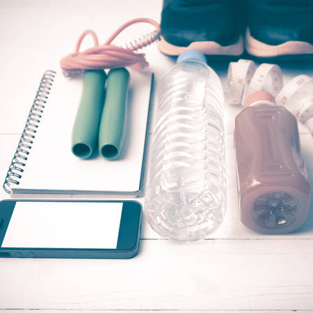 fitness equipment:running shoes,jumping rope,notepad,phone,water,juice and measuring tape on white...
