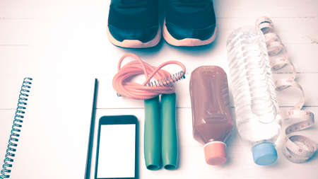 fitness equipment:running shoes,jumping rope,notepad,phone,water,juice and measuring tape on white...