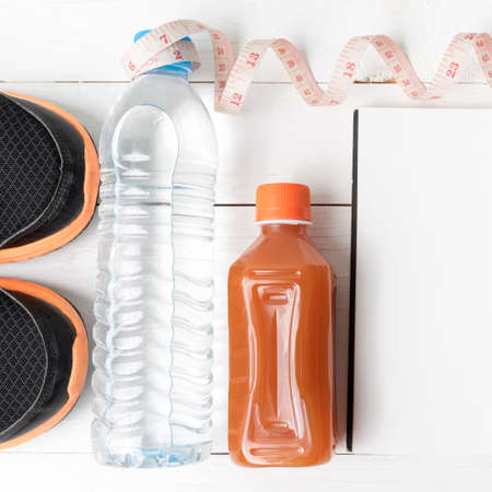 fitness equipment:running shoes,water,measuring tape,notepad,phone and juice on white wood backgroundの写真素材