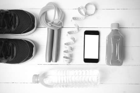 fitness equipment:running shoes,phone,measuring tape,water,juice and jumpong rope on white wood...