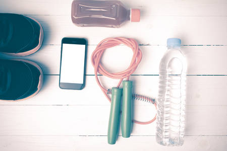 fitness equipment : running shoes,jumping rope,water,juice and phone on white wood background vintage styleの写真素材