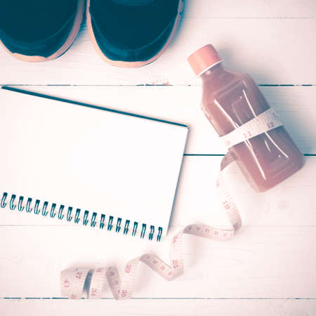 fitness equipment:running shoes,juice,measuring tape,notepad and phone on white wood background vintage styleの写真素材