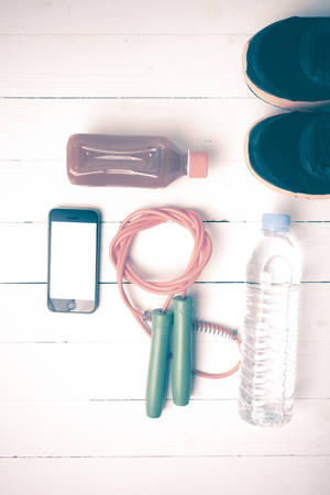 fitness equipment : running shoes,jumping rope,water,juice and phone on white wood background vintage styleの写真素材