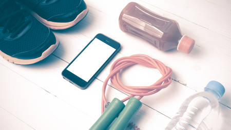 fitness equipment : running shoes,jumping rope,water,juice and phone on white wood background vintage styleの写真素材