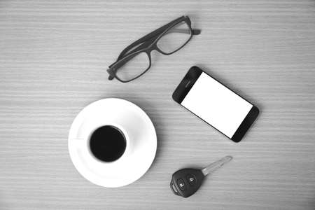 coffee cup and phone with car key on wood background black and white colorの写真素材