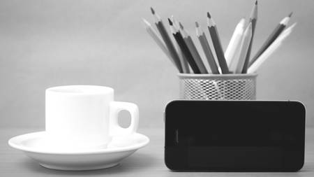 coffee cup and phone with color pencil on wood background black and white colorの写真素材