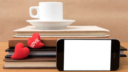 coffee,phone,stack of book and heart on wood table background