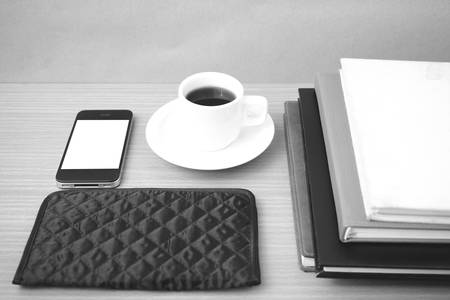 coffee,phone,stack of book and wallet on wood table background black and white color
