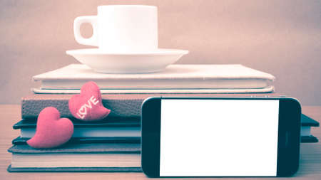 coffee,phone,stack of book and heart on wood table background vintage styleの写真素材