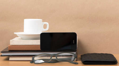 coffee,phone,eyeglasses,stack of book and wallet on wood table backgroundの写真素材